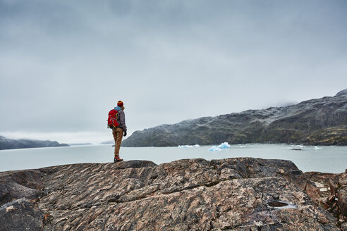 Chile, Torres del Paine National park, Lago Grey, woman standing on rock at the shore looking at iceberg - SSCF00278