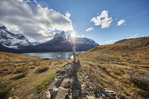 Chile, Torres del Paine National park, woman standing on rock in front of Torres del Paine massif at sunrise stock photo