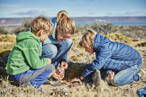 Argentinien, Rio Chico, Frau und Söhne sammeln Steine in der Steppe, lizenzfreies Stockfoto
