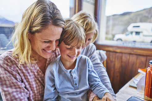 Glückliche Mutter mit zwei Söhnen sitzt am Tisch in einem Café - SSCF00317