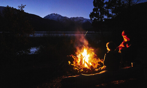 Argentinien, Patagonien, Lago Futalaufquen, Mutter mit Söhnen am Lagerfeuer bei Nacht, lizenzfreies Stockfoto