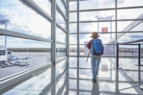 Junge mit Rucksack auf dem Flughafen, der zum Abfluggate läuft - SSCF00346