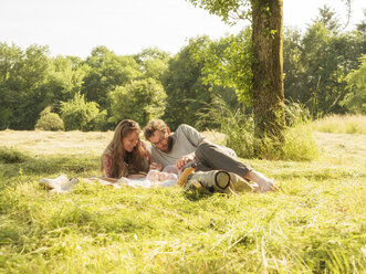 Young couple relaxing with baby girl on blanket in nature - LAF02187