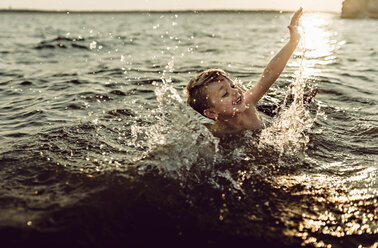 Carefree boy swimming in river - CAVF59214