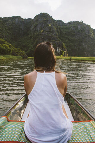 Rückansicht einer Frau, die in einem Boot auf einem Fluss fährt, lizenzfreies Stockfoto