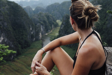 Seitenansicht einer Frau, die auf einem Berg sitzend die Aussicht betrachtet - CAVF59237