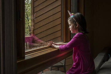 Seitenansicht eines Mädchens, das zu Hause am Fenster sitzt - CAVF59268