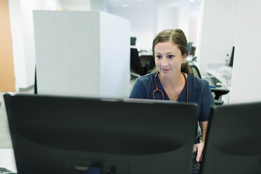 Selbstbewusste Ärztin bei der Arbeit mit einem Desktop-Computer im Krankenhaus - CAVF59277