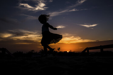 Low angle view of silhouette girl dancing on field against sky during sunset - CAVF59299