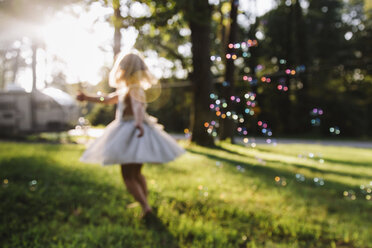 Girl dancing while playing with bubbles at park - CAVF59300