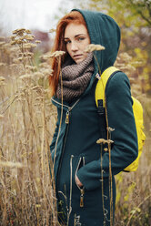 Portrait of teenage girl with backpack standing amidst plants - CAVF59331