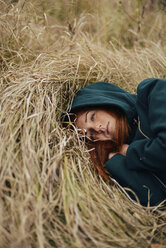 High angle thoughtful of teenage girl lying on grassy field - CAVF59336