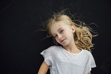 Portrait of girl standing against black background - CAVF59345