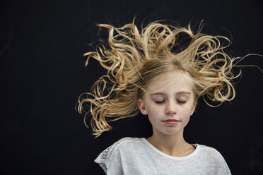 Girl with eyes closed standing against black background - CAVF59346