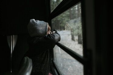 Boy looking through window while sitting in tour bus at Yosemite National Park - CAVF59348