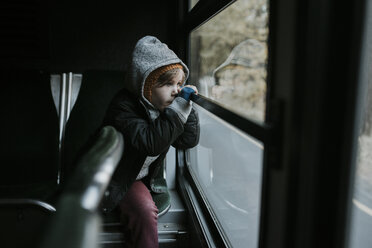 Thoughtful boy looking through window while sitting in tour bus at Yosemite National Park - CAVF59349