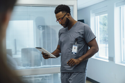 Arzt benutzt Tablet-Computer beim Gehen im Krankenhaus, lizenzfreies Stockfoto
