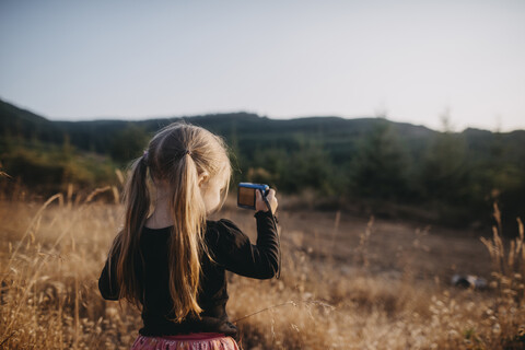 Mädchen mit Zöpfen fotografiert auf einem Feld stehend, lizenzfreies Stockfoto