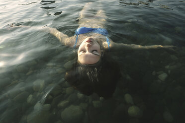 High angle view of carefree woman with eyes closed floating on water in river - CAVF59468