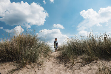 Niedriger Blickwinkel des Jungen stehend auf Sand am Strand gegen den Himmel während des sonnigen Tages - CAVF59503