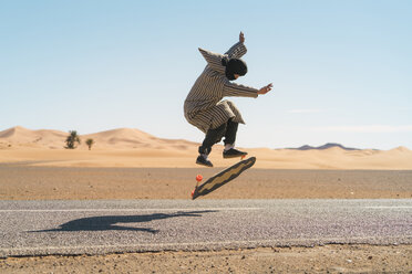 Side view of man jumping while skateboarding on road against sky - CAVF59572