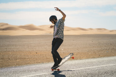 Man skateboarding on road during sunny day - CAVF59573