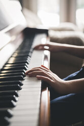 Cropped image of boy playing piano at home - CAVF59584