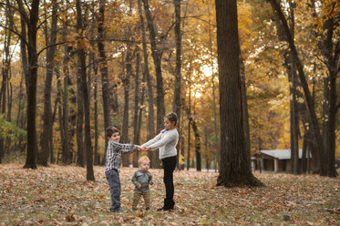 Siblings playing on field at park during autumn - CAVF59623
