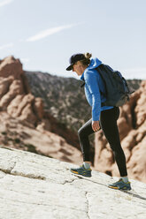 Seitenansicht einer Wanderin mit Rucksack, die an einem sonnigen Tag auf einem Berg wandert - CAVF59637