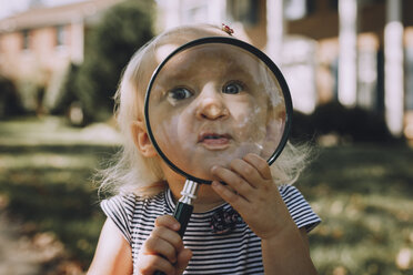 Portrait of playful baby girl with magnifying glass - CAVF59675