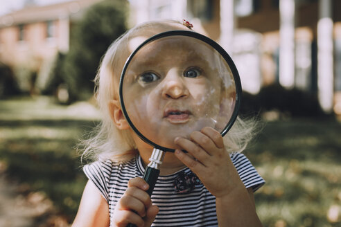 Porträt eines verspielten kleinen Mädchens mit Vergrößerungsglas - CAVF59675