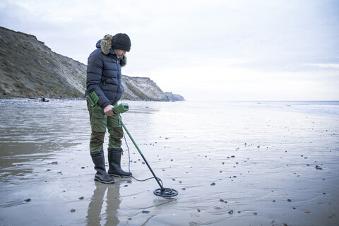 Man with metal detector at the sand beach stock photo