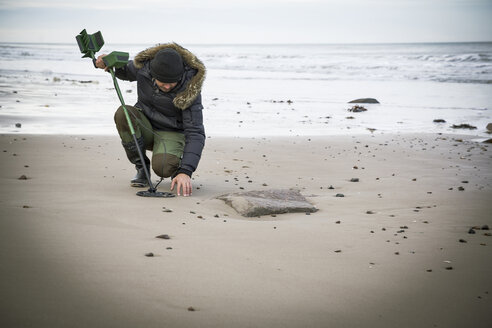 Mann mit Metalldetektor am Sandstrand - REAF00507