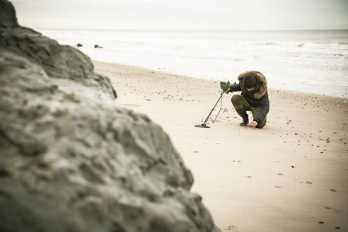 Mann mit Metalldetektor am Sandstrand - REAF00508