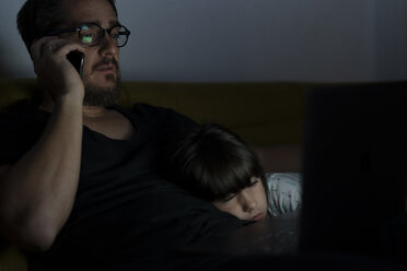 Vater telefoniert nachts auf der Couch, während seine Tochter schläft - ERRF00305