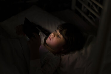 Mädchen liegt im Bett und benutzt nachts ihr Smartphone - ERRF00310