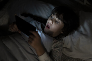 Portrait of little girl lying on bed in underwear looking at