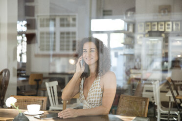 Mature woman sitting in coffee shop, talking on the phone - MOEF01888