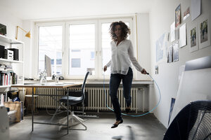 Businesswoman in office, training with skipping rope - MOEF01889