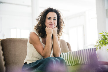 Confident woman sitting on her couch, smiling - MOEF01905