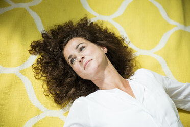 Tagträumende Frau auf gelbem Teppich liegend - MOEF01920
