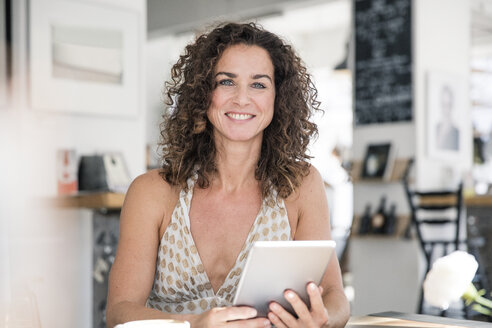 Ältere Frau sitzt in einem Café und benutzt ein digitales Tablet - MOEF01925