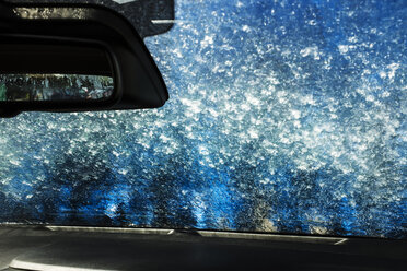 Blick aus dem Inneren eines Autos in einer automatischen Autowaschanlage, blaue Waschanlagen und Seifenwasser über den Scheiben. - MINF09714