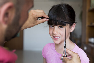 Father cutting daughter's hair at home - ERRF00317