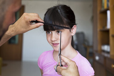 Father cutting daughter's hair at home - ERRF00318