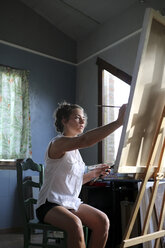 Junge Frau malt in ihrem Atelier - ERRF00329