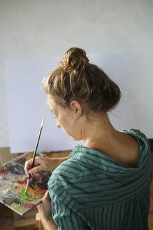 Junge Frau mit Palette malt in ihrem Atelier - ERRF00331