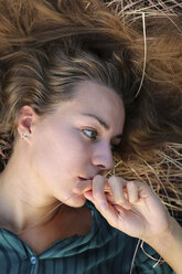 Portrait of young woman lying on straw - ERRF00332