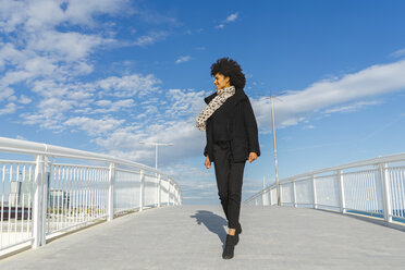 Spanien, Barcelona, lächelnde, schwarz gekleidete Frau beim Überqueren einer Brücke - AFVF02067