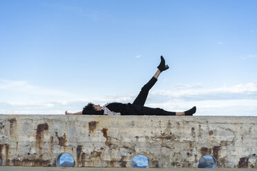 Woman dressed in black relaxing on a wall - AFVF02090